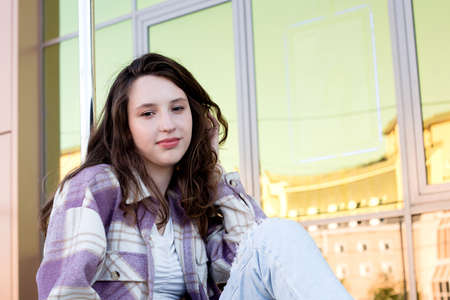 One smiling girl is sitting on the street. Lifestyle.