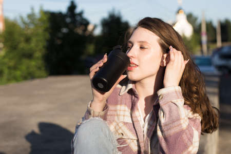 A girl with a mug in her hand on the street. Beautiful people.の写真素材