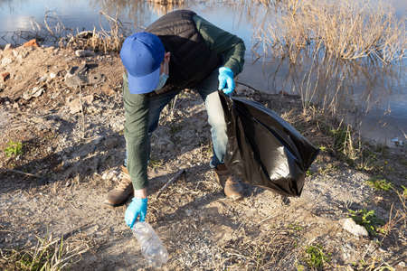 A volunteer collects empty plastic bottles. The concept of ecology and environmental protection.