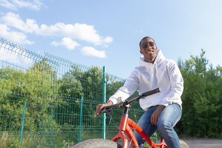 A smiling man rides a bicycle in a public park. sports and recreation.