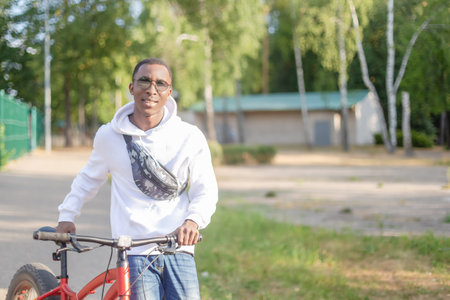 A smiling happy man with a bicycle in a public park. sports and recreation.の写真素材