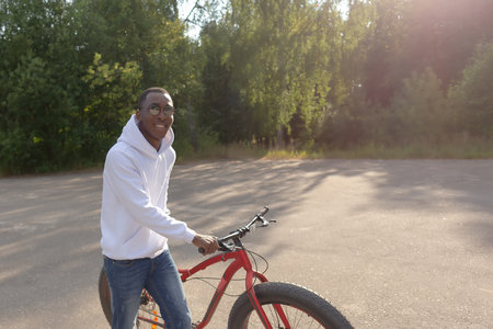 A happy smiling man with a bicycle in a public park. sports and recreation.の写真素材