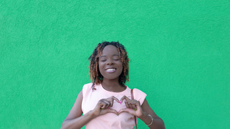 Smiling happy woman on a green background. love. Gestures. positive emotions.の写真素材