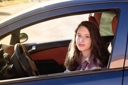 A beautiful happy woman is sitting in the car. car dealership. Car rental and sale.