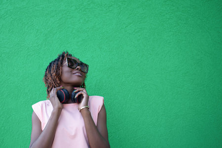 A smiling African-American woman listens to music with headphones. Wireless technologies. Copy space.の写真素材