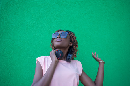 A smiling African-American woman listens to music with headphones. Wireless technologies.の写真素材