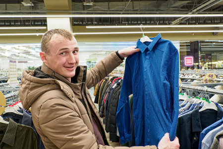 A smiling man chooses a shirt. Casual clothes. Clothing stores. Textile industry.の写真素材