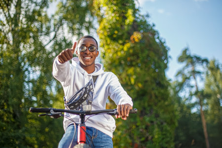 A smiling man rides a bicycle through a public park. An active lifestyle.