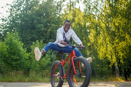 A smiling man rides a bicycle through a public park. Sports and recreation.