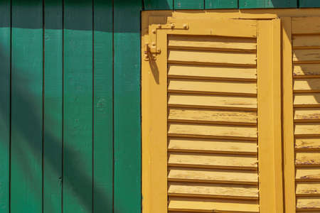 a yellow window on a green shed
