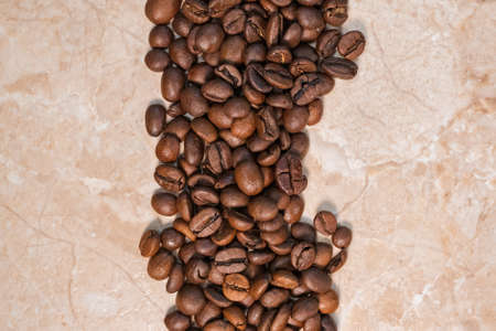 sprinkled roasted coffee beans on white and yellow marble top viewの写真素材
