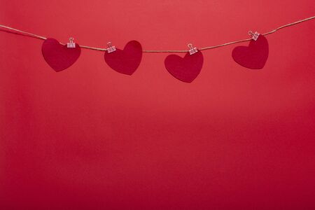 Decorative clothespins with hearts on a rope on a red background for Valentine's Day, wedding,...