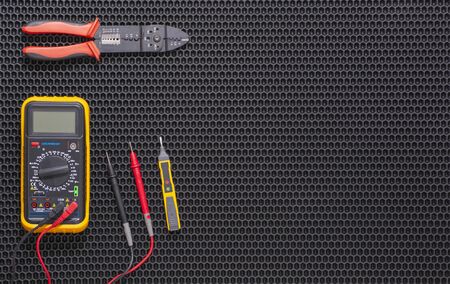 Multimeter, indicator screwdriver and wire stripper on a black rubber matの写真素材