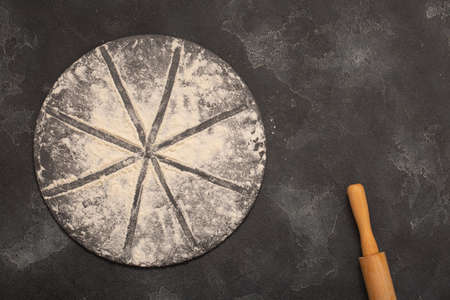 Drawing of flour in the form of a pizza and a rolling pin on a gray stone background. Free space for text . Top viewの写真素材