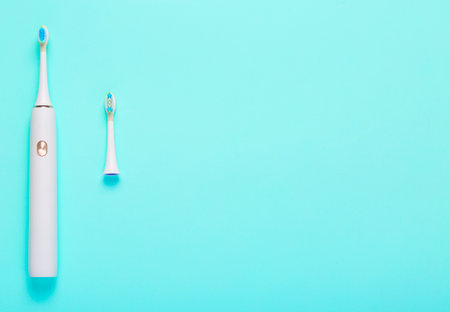 Electric toothbrush and extra brush head on blue medical background. Free space for text. top view. Close-up. copy spaceの写真素材