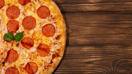 Tasty fresh pepperoni pizza and ingredients tomatoes basil on wooden background. Top view of pepperoni pizza. Flat lay. With copy space for text. Bannerの写真素材