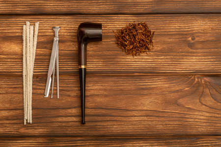 Smoking pipe, tobacco and cleaning tool on wooden background.の写真素材