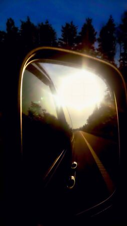 car mirror reflection of the morning sun in the mirror the terrain in the background close-up