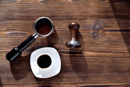 white coffee cup with saucer barista accessories for making coffee temper and coffee horn, morning side light wooden natural background close-up copy spaceの写真素材