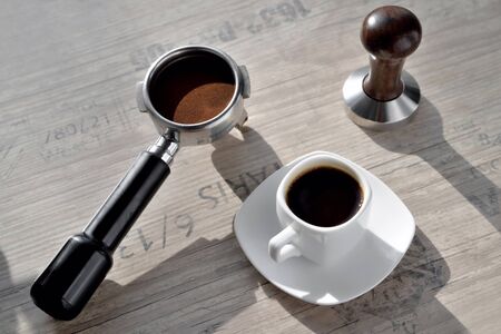 white coffee cup with saucer barista accessories for making coffee temper and coffee horn, morning side light background old port oak close-upの写真素材