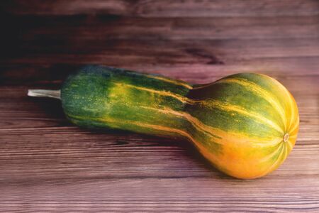 Yellow-green oblong shaped pumpkin, natural wooden background, diet food, Halloween close-upの写真素材