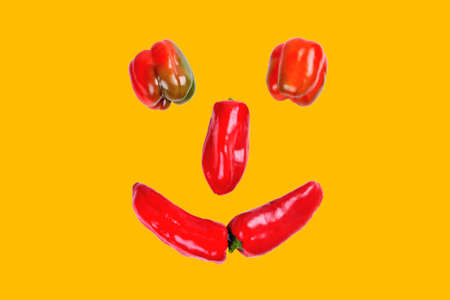 sweet pepper, smil laid out of red sweet pepper, funny face of red pepper on a yellow background close-upの写真素材