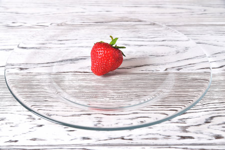 Strawberries in a transparent glass plate on a light natural background close-up copy spaceの写真素材