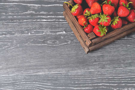 Strawberries in a natural wooden box on a natural wooden grau background, selekcive focus close-up copy spaceの写真素材