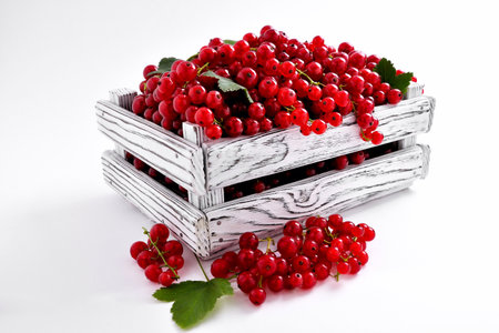 red currant in wooden rustic light box on white background close-up selective focusの写真素材