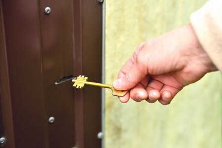 entrance door, female hand with yellow key at the door close-up selective focusの写真素材