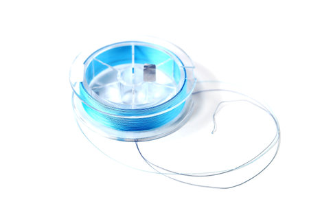Braided blue line for fishing on a transparent coil, isolate, close-up