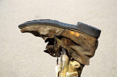 Old torn Shoe hanging on a stick.Leather shoes wrinkled.