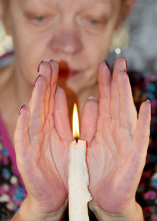 A woman framed palm to the burning candle and warms them.の写真素材