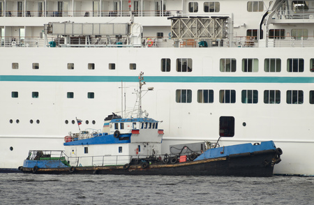 A small boat next to the cruise ship .The vehicle is refilled with fuel .の写真素材