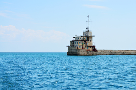 In the sea stands a lighthouse.Blue waves on the sea surface.の写真素材