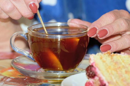 Woman spoon prevents sugar in a cup of tea. To drink was sweet.の写真素材