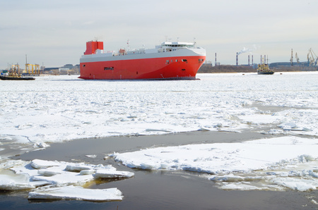 Cargo ship in the waters of the port.The water in the Bay is covered with ice.の写真素材