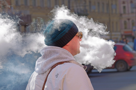 Saint-Petersburg.Russia.April.7.2018.A man smokes on the street electronic cigarettes.Around the person a lot of smoke.It's bad for your health.のeditorial素材