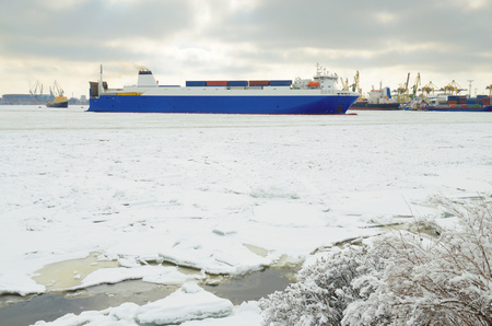 Cargo ship in the waters of the port.The water in the Bay is covered with ice.の写真素材