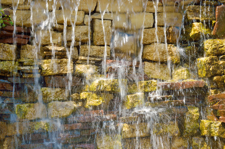 Water flows through the stone wall.It is a beautiful miniature waterfall.の写真素材