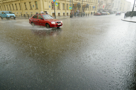 It is raining heavily in the city.On the roads are large puddles.のeditorial素材