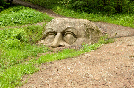 Stone head of unknown origin.Is in the forest half in earth.の写真素材