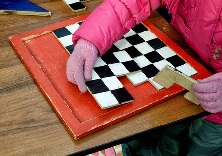 The child on the table collects wooden golovolomka.の写真素材