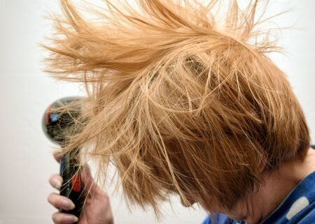The woman washed her hair. Then she dries her hair with a hairdryer.の写真素材