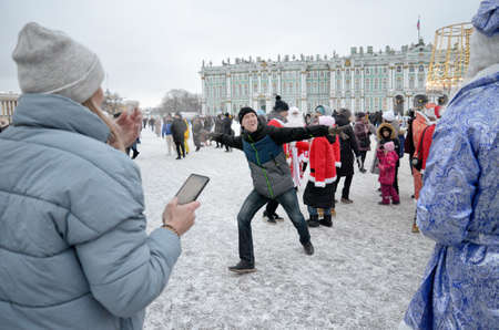 Saint-Petersburg.Russia.January 03.2022. New Year's festivities at the Palace Square Santa Claus gives gifts to children. People dance, have fun, lead round dances.のeditorial素材