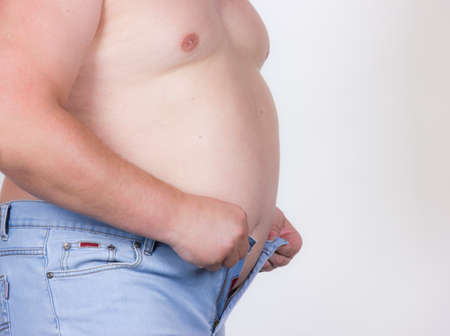 Man tries to fasten pants on the large belly の写真素材