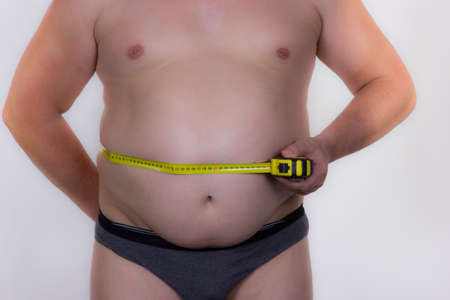 Stripped man is measuring her belly in the volumeの写真素材