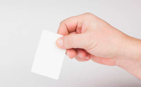 Hand holding a business card on a gray background