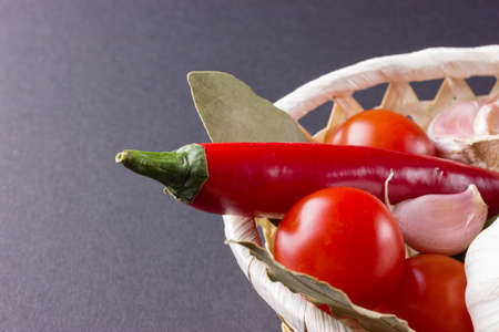 Vegetables in basket with garlic and chilli with bay leaf.の写真素材