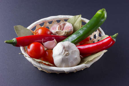 Vegetables in basket with garlic and chilli with bay leaf.の写真素材